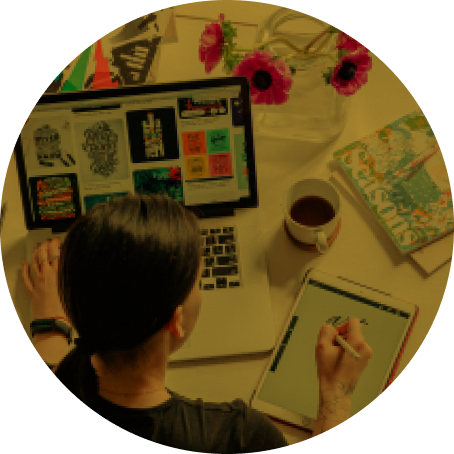 A person reviews designs on a laptop and sketches ideas using a smart pen and tablet