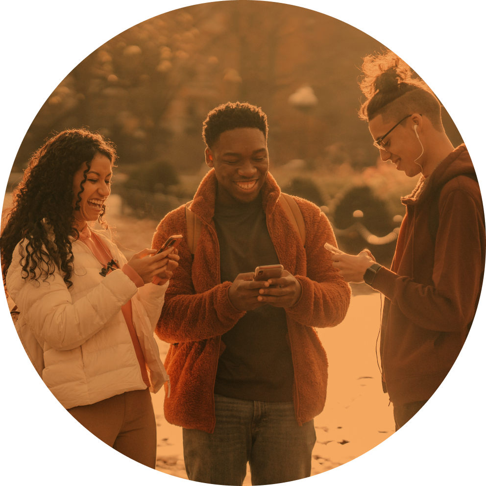 Three people smile and laugh while using their smartphones