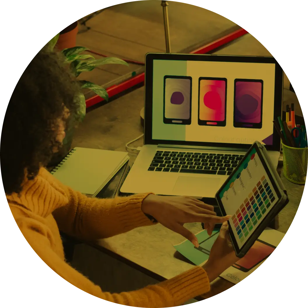 A person reviews designs on a laptop and sketches ideas using a smart pen and tablet