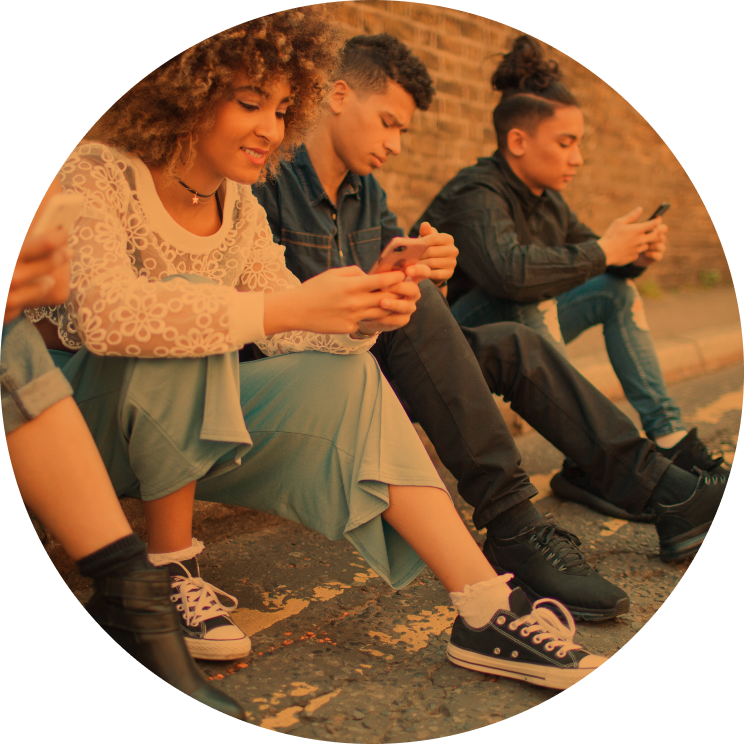 Three people smile and laugh while using their smartphones